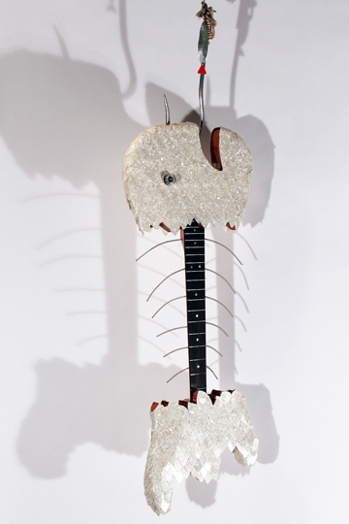 small electric guitar in the shape of a fish with the middle body as a skeleton