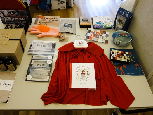 a table with a red riding hood cape and miscellaneous merch