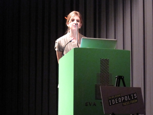 a young lady giving a speech from a green stand