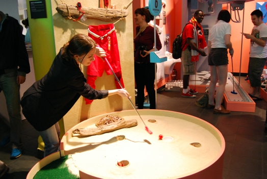 a girl is trying to guide a golf ball into the hole of a mini-golf course