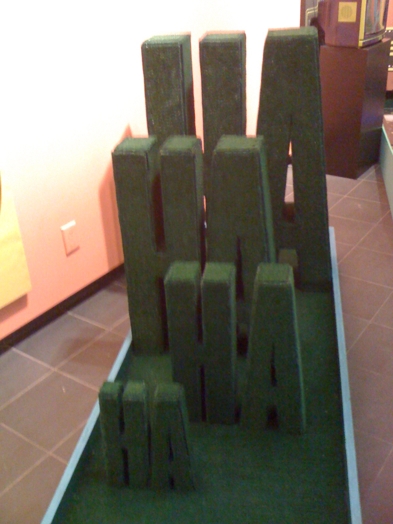 sculpture made of a green material illustrating "ha ha ha ha" made from the small scale for the first word, going bigger and bigger to the fourth word