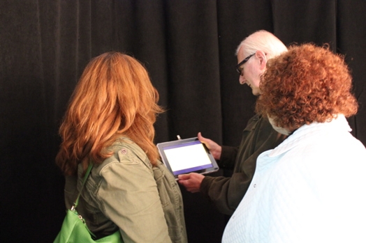 three people looking with interest at an iPad screen in the exhibition room