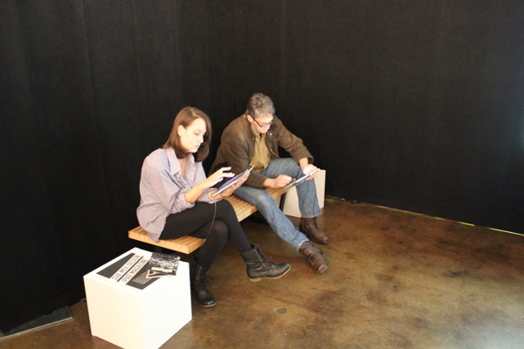 two people sitting on a bench with iPads in their hands