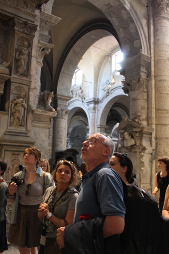 A photo of a group of people visiting a cathedral and its arches sculpted in stone.