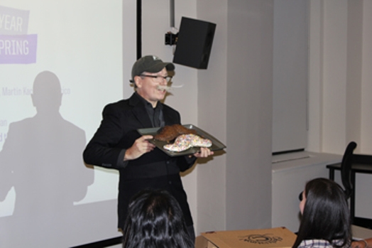 a man dressed in a black suit presenting to the public a plate with two rounded shaped objects