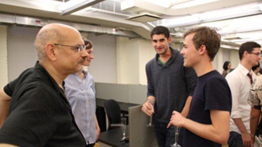 a group of men is talking in a well-lit room