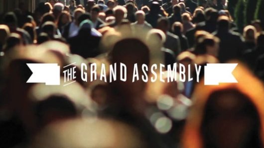 the grand assembly logo was placed over an image of a crowd on the sidewalk