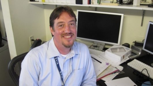 portrait of a man sitting at it desk near computers