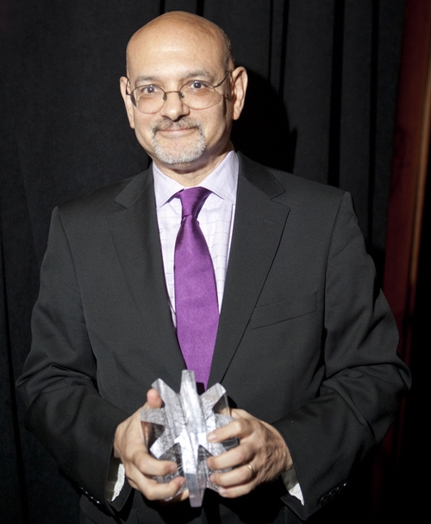 portrait of a man in a suit and a purple tie holding his prise with both hands