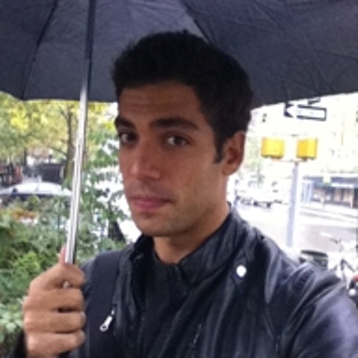 portrait of a man outside in the rain holding a black umbrella