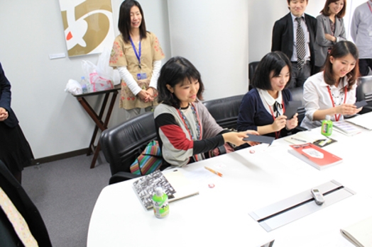 people sitting at a table with pens, rulers, and notepads