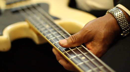 close-up of an electronic guitar held with one hand by a person