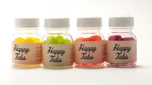 four happy jars with yellow, green, orange and red pills