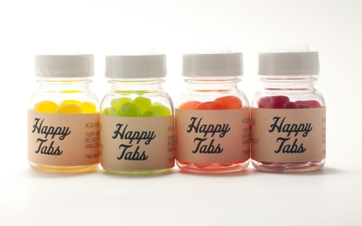 four happy jars with yellow, green, orange and red pills