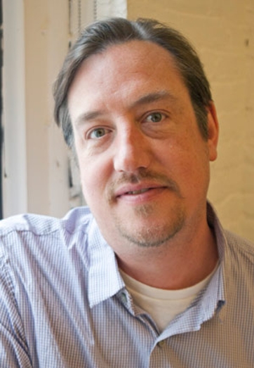 portrait of a man with a blue shirt near a window