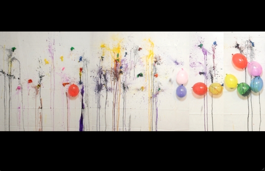 a wall with colored balloons and paint spots draining down the wall