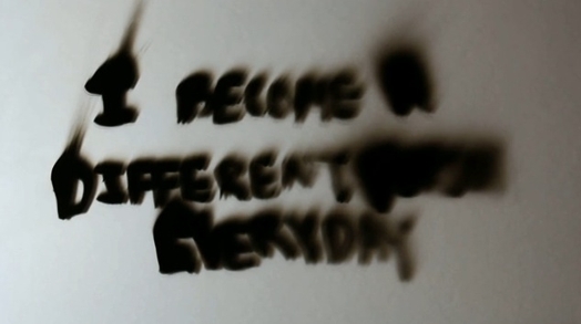 "i become a different person everyday" written with a marker on a reflective surface and its being dissolved and distorted