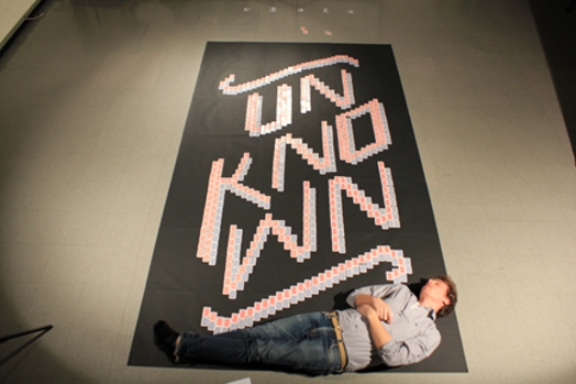 unknown banner laid on the floor and a man is sitting on the bottom part of it