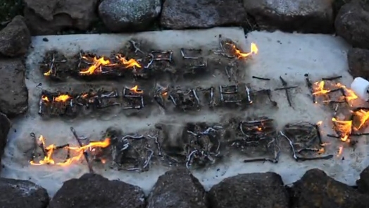 an arrangement surrounded with stones and the words formed with sticks: the best investment is in yourself; the wording is set on fire
