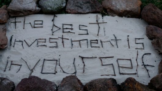an arrangement surrounded with stones and the words formed with sticks: the best investment is in yourself