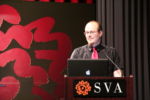 a man giving a speech from a stand in the "designer as" thesis presentation