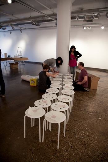 people preparing the chairs with stickers for the designer as exhibition