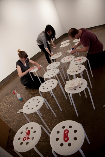 people preparing the chairs with stickers for the designer as exhibition