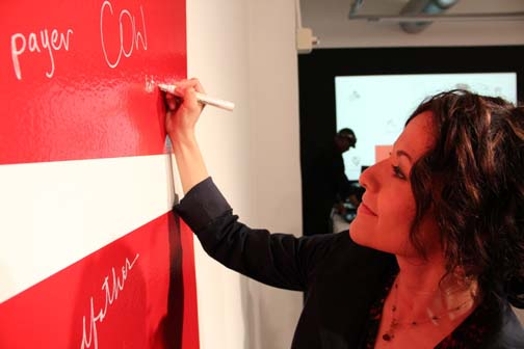 woman writing with a white pencil on a red wall