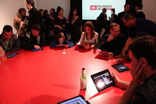 people sitting around a table and watching content on tablets