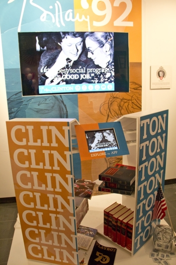 election exhibition with Clinton's name on a shelf and a TV in the back