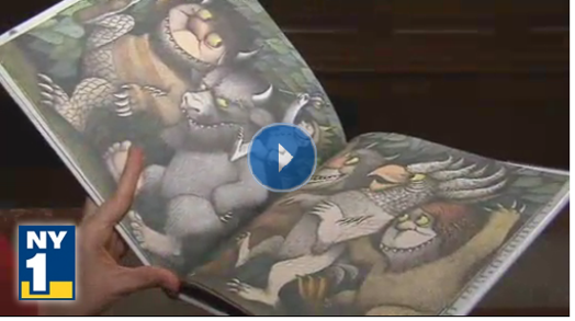 still from the news with a person having an opened illustration book in hand