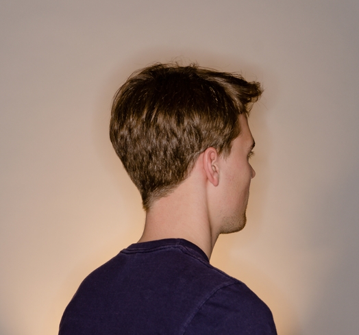 photo of a young man sitting with his back profile to the camera