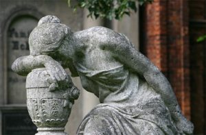 photo of a statue of a woman resting her head on her arm, which is also resting on a vase