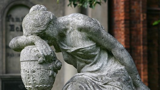 photo of a statue of a woman resting her head on her arm, which is also resting on a vase