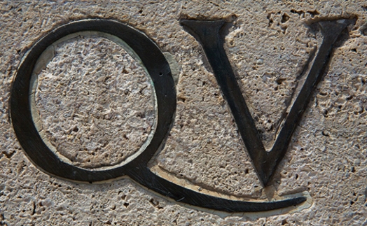 metal letters Q and V embedded in stone wall