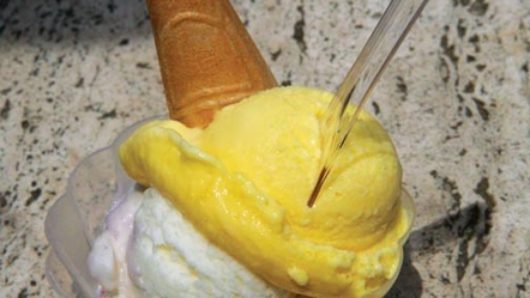 yellow and white gelato in a cup with a spoon and a cone