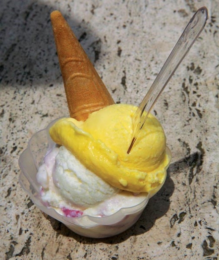 yellow and white gelato in a cup with a spoon and a cone