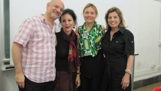 three women and one man in front of projection board