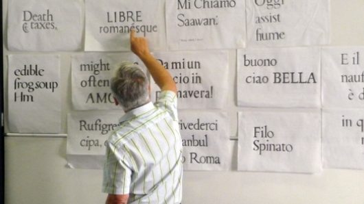 men pointing at typography on wall filled with papers