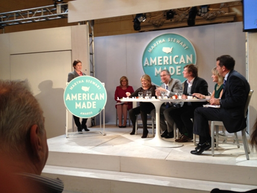 a woman giving a speech on the stand with the Martha Stewart American Made awards logo and in front of a jury