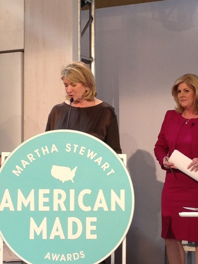 a woman giving a speech on the stand with the Martha Stewart American Made awards logo