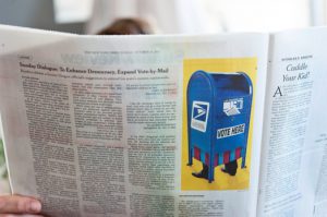 A photo of a newspaper with a picture of a blue mailbox with feet on it.