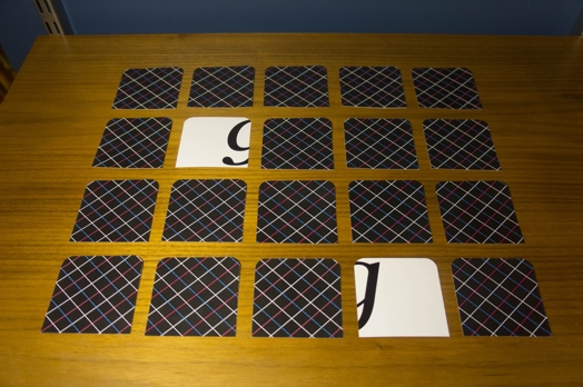 A photo of a set of tiles, two of them being turned, that form the letter g.