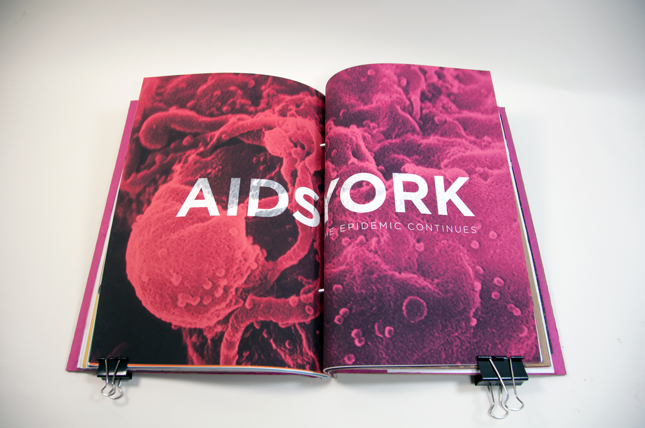 an opened book with a pink image and AIDSYORK written on it