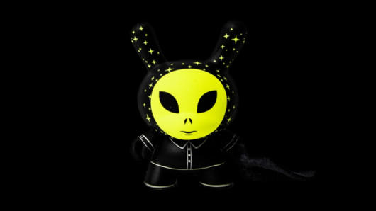 a small alien figurine painted in neon green with the hood with small stars painted with glow in the dark green