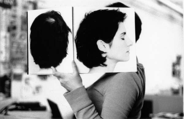 A black and white photo of a woman holding a book with a picture of her from behind and from a side.