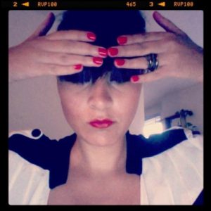 A photo of a woman wearing a black and white dress while holding her fingers on top of her head.
