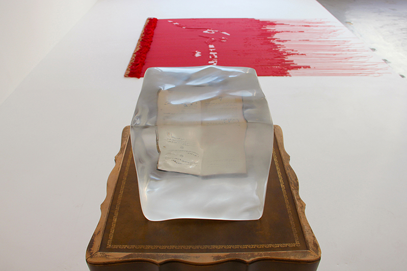 A wooden chair with a transparent acrylic cube with a book in it.