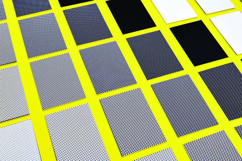 a grid of grey and black papers with the dotted pattern on them arranged on a yellow table