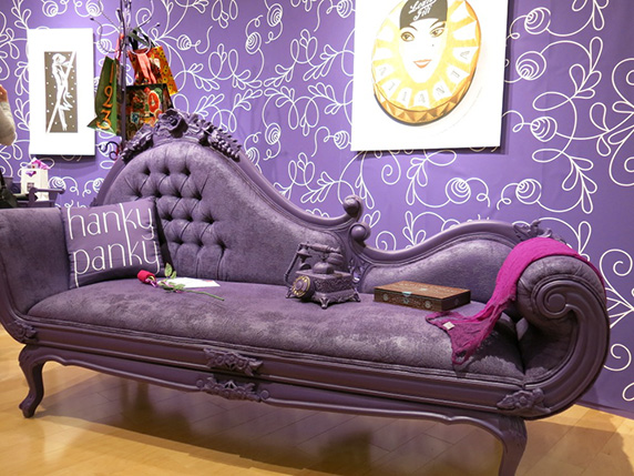 a purple vintage couch next to a wall with a purple wallpaper with rounded white lines as a pattern